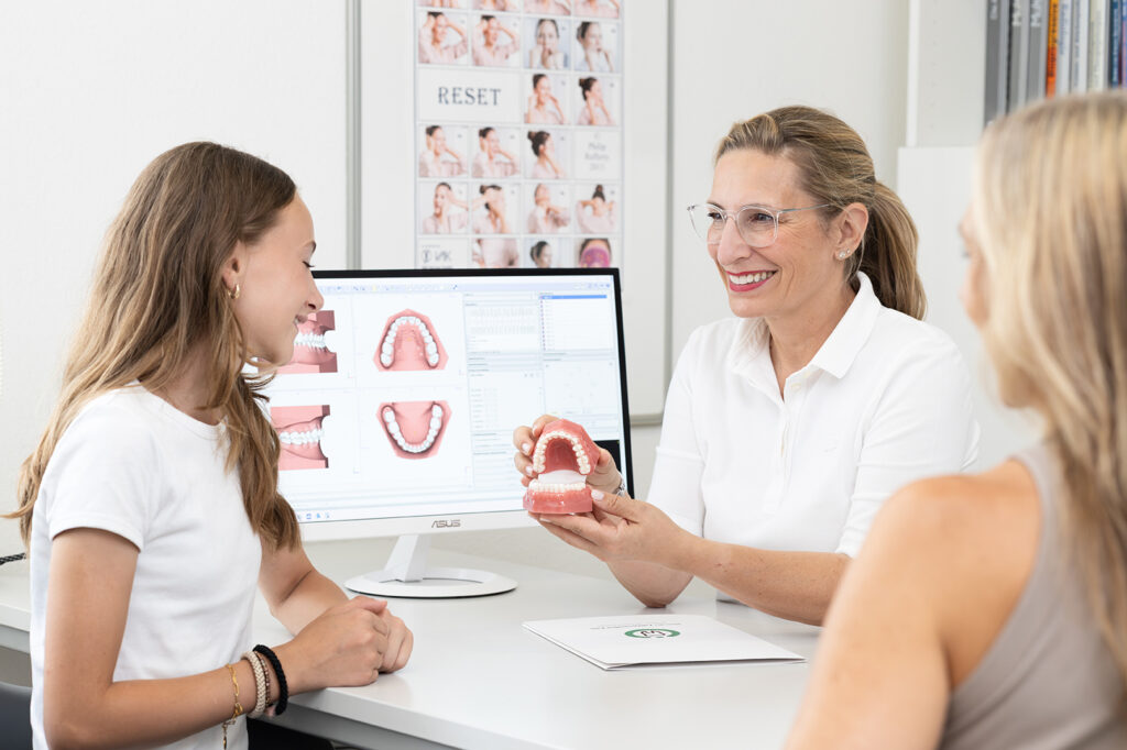 Dr. Paula Göser erklärt Patientin und Mutter die ganzheitliche Kieferorthopädie im Haus der Zahngesundheit Köln
