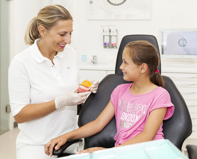 Dr. Paula Göser erklärt einem jungen Mädchen die lose Zahnspange – moderne, ganzheitliche Kieferorthopädie im Haus der Zahngesundheit Köln