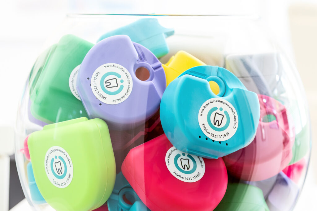 Bunte Zahnspangendosen in Schale – Symbol für verschiedene Zahnspangenarten im Haus der Zahngesundheit Köln